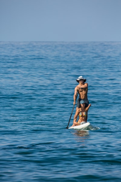 During the day in the midst of the sea on the white board in blue bikini woman
